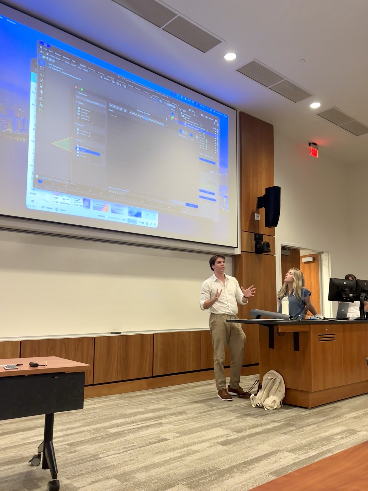 Tyler presenting a live demonstration beside a projected computer screen.